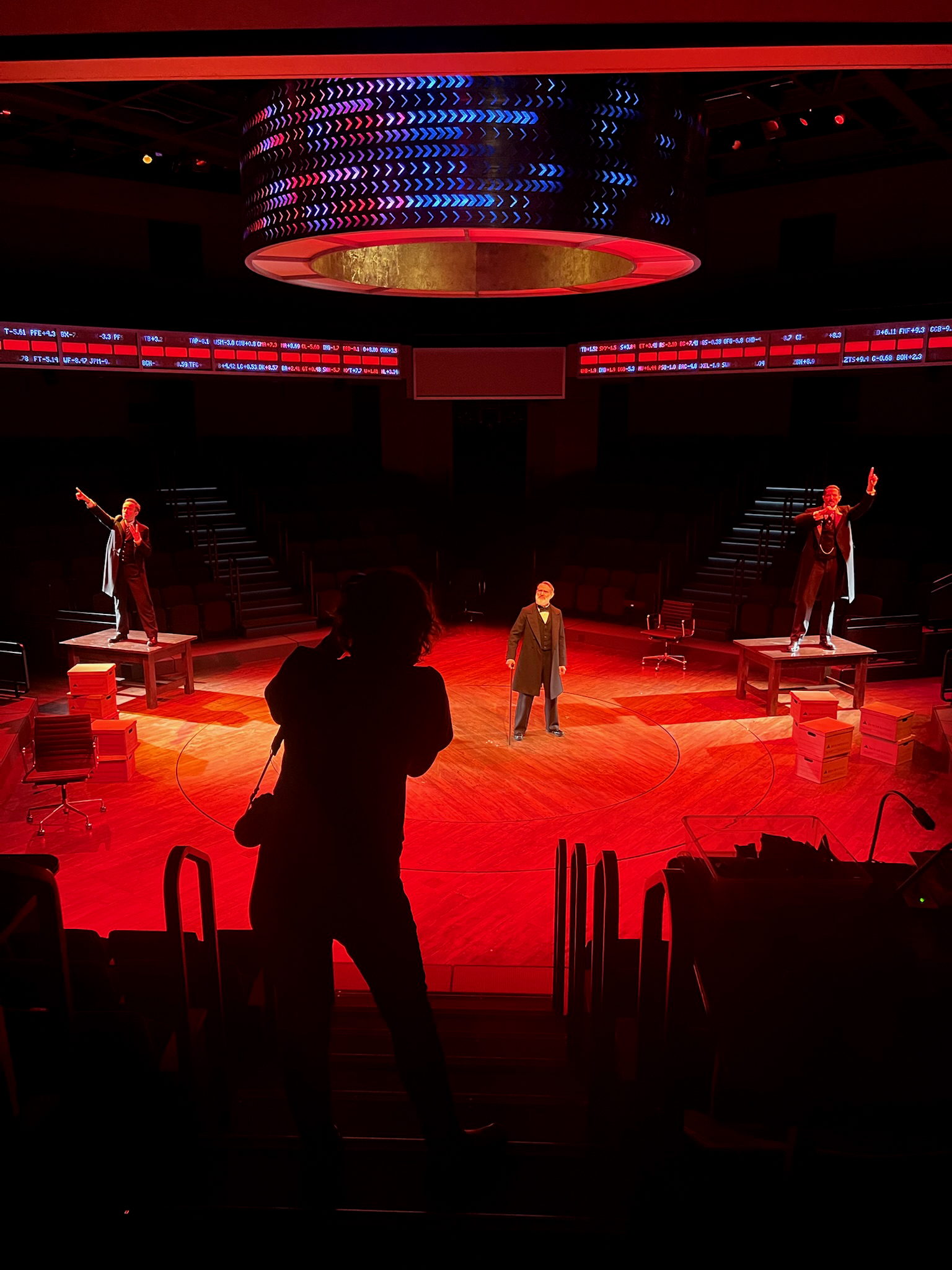 Silhouette of photographer in a theater, with three actor's in the background